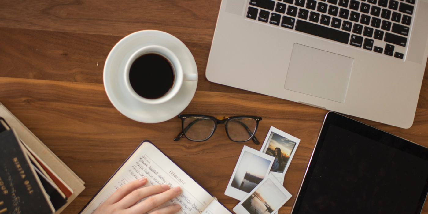 A workdesk with notebooks, a cup of coffee and a laptop